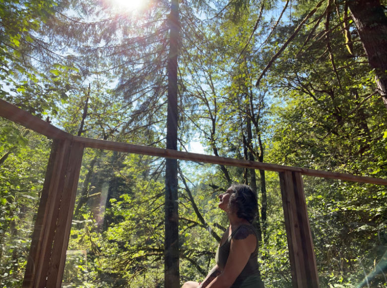 A woman looks up at the sunlight filtering through the trees